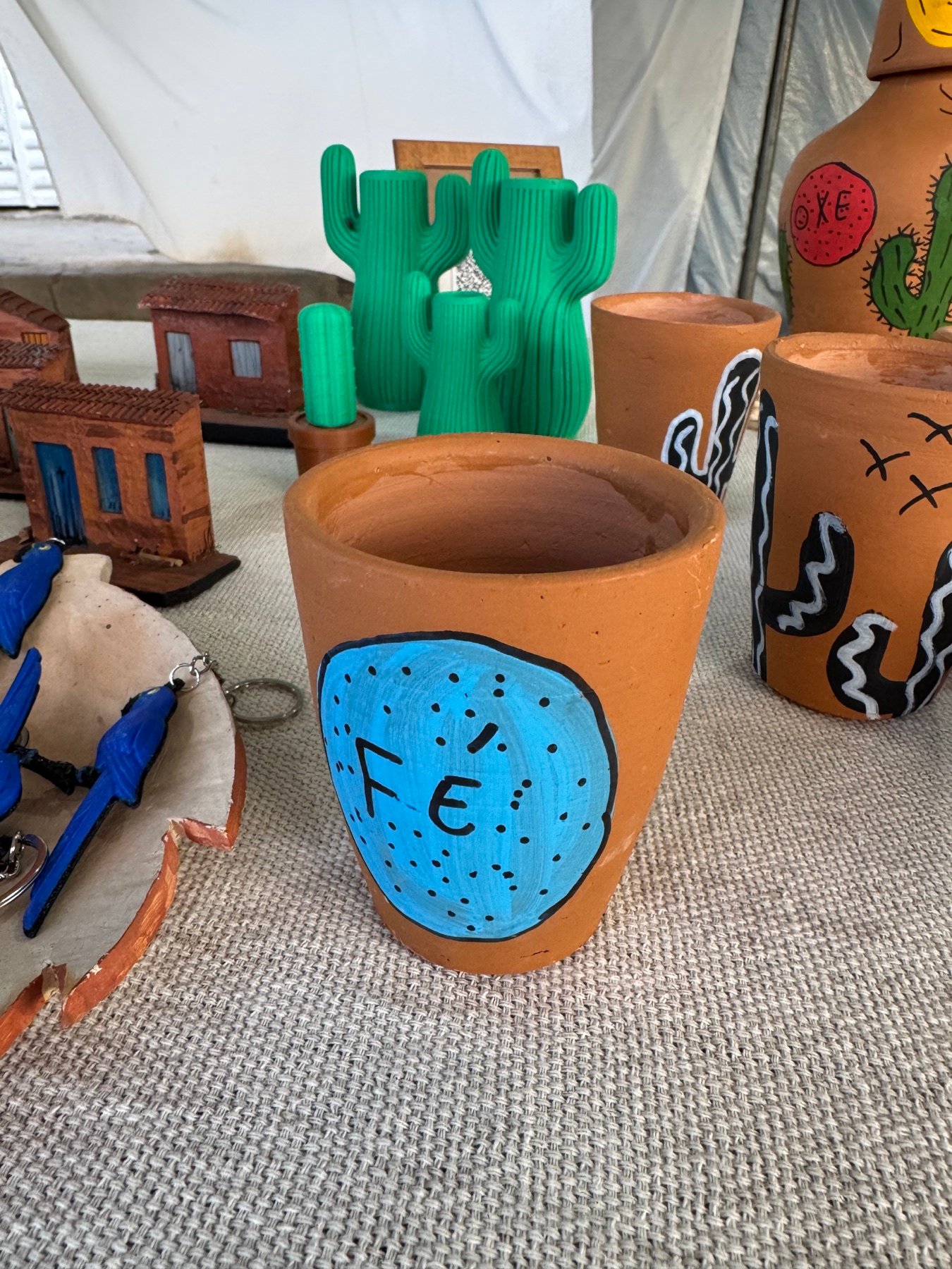 Copo artesanal em barro com a palavra Fé pintada em azul